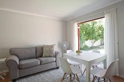 a living room with a couch and a table and chairs at Sunbird Cottage in Somerset West