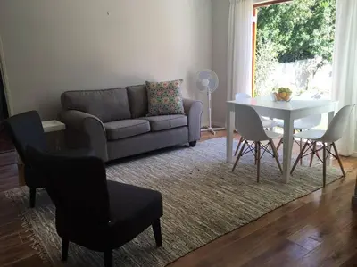 a living room with a couch and a table and chairs at Sunbird Cottage in Somerset West