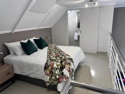a bedroom with a bed with green pillows at Beautifully furnished loft apartment in central Durbanville in Durbanville
