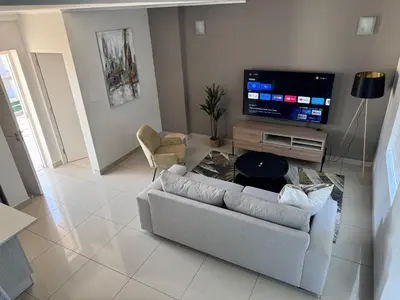 a living room with a couch and a flat screen tv at Beautifully furnished loft apartment in central Durbanville in Durbanville