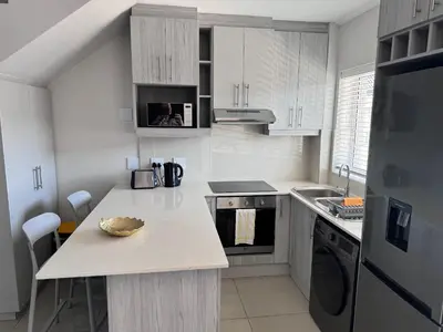 a kitchen with white cabinets and a counter top at Beautifully furnished loft apartment in central Durbanville in Durbanville