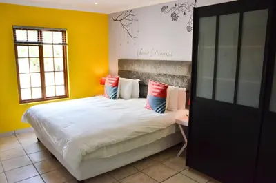 a bedroom with a large bed with yellow walls at Kleinbosch Lodge in Stellenbosch