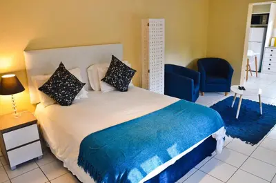 a bedroom with a large bed with blue sheets and pillows at Kleinbosch Lodge in Stellenbosch