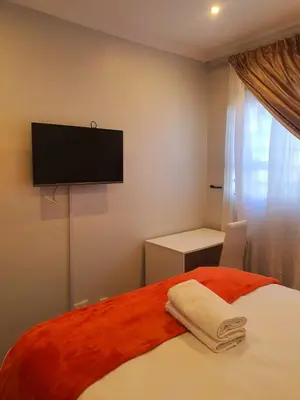 a bedroom with a bed with a flat screen tv on the wall at ELMED GUEST HOUSE in Cape Town