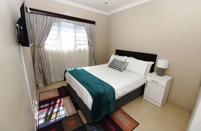 a small bedroom with a bed and a window at ELMED GUEST HOUSE in Cape Town
