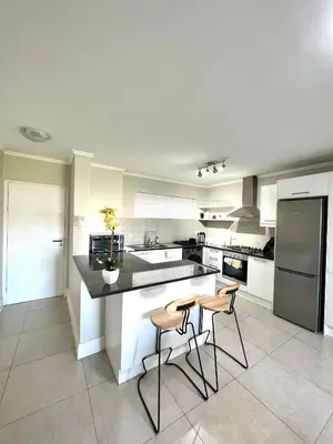 a kitchen with two stools and a counter with a refrigerator at Ashton Park 221 in Cape Town
