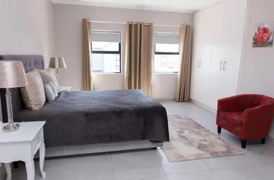 a bedroom with a bed and a red chair at MLMK Property 17 in Cape Town