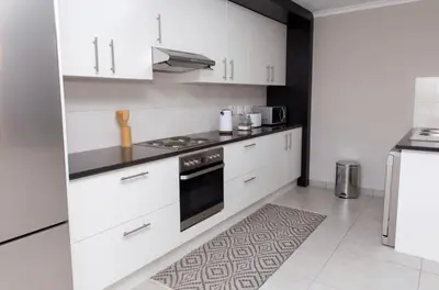 a kitchen with white cabinets and a stove top oven at MLMK Property 17 in Cape Town