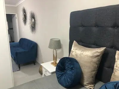 a living room with a couch and a blue chair at MLMK Property Studio17 in Cape Town
