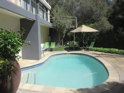a large blue swimming pool next to a building at Pecan Tree Forest Studio A in Stellenbosch