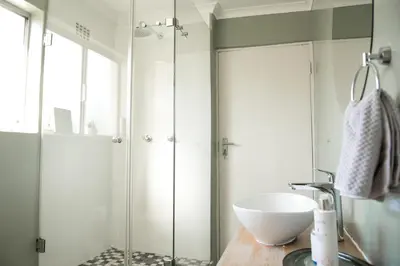 a bathroom with a sink and a glass shower at Easy Going Hermanus With An Ocean View in Hermanus