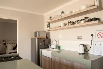 a kitchen with a sink and a refrigerator at Easy Going Hermanus With An Ocean View in Hermanus