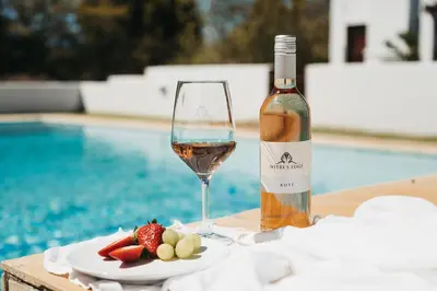 a bottle of wine and a plate of fruit next to a pool at Mitre's Edge Pool House in Klapmuts