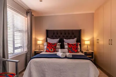 a bedroom with a large bed with two lamps at Tortelduif Cottage in Stellenbosch