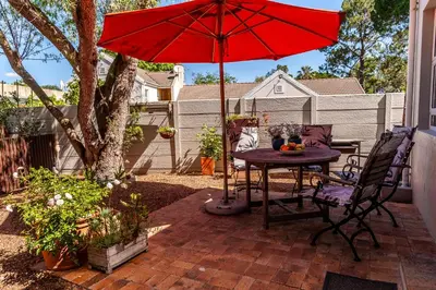 a patio with a table and a red umbrella at Tortelduif Cottage in Stellenbosch