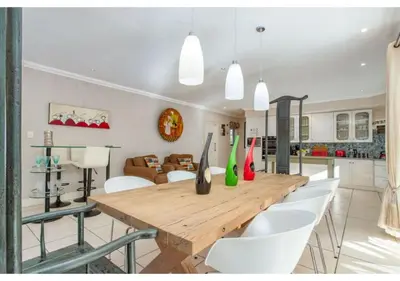 a dining room with a wooden table and white chairs at Florin’s Crest 3 Bedroom Villa, Franschhoek in Franschhoek