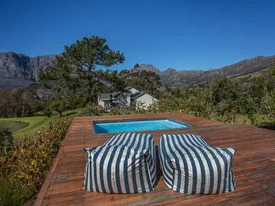 two pillows sitting on a wooden deck with a swimming pool at Wechmarshof in Stellenbosch