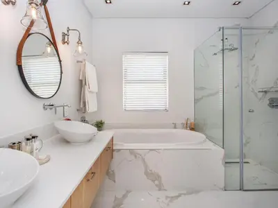 a white bathroom with a tub and a sink at Wechmarshof in Stellenbosch