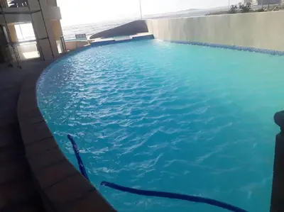 a large swimming pool with blue water in a building at Beautiful Ocean View Apartment in Cape Town