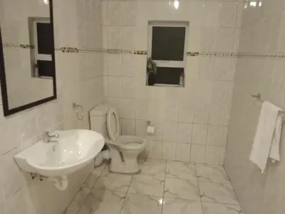 a white bathroom with a toilet and a sink at Jacmo Guest house in Cape Town