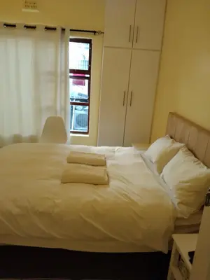 a bedroom with a white bed with towels on it at Jacmo Guest house in Cape Town