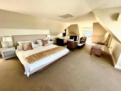 a bedroom with a large bed and a living room at 11 WESTCLIFF RENTALS in Hermanus