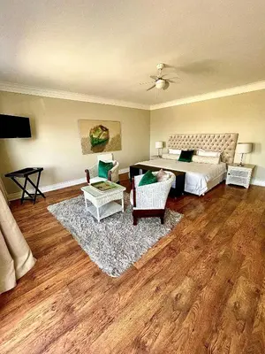 a bedroom with a bed and two chairs and a rug at 11 WESTCLIFF RENTALS in Hermanus