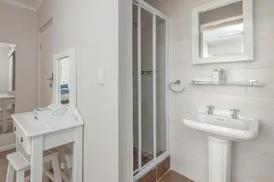 a white bathroom with a sink and a mirror at Mountain View by Top Destinations Rentals in Hermanus