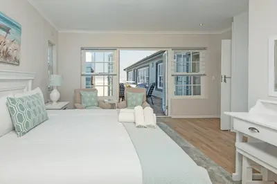 a white bedroom with a large bed and a living room at Mountain View by Top Destinations Rentals in Hermanus