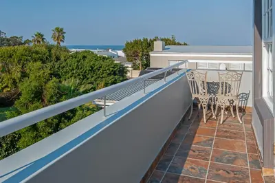 a balcony with two chairs and a table at Mountain View by Top Destinations Rentals in Hermanus