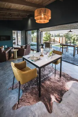a dining room with a table and chairs on a rug at Bains View Olive and Guest Farm in Wellington