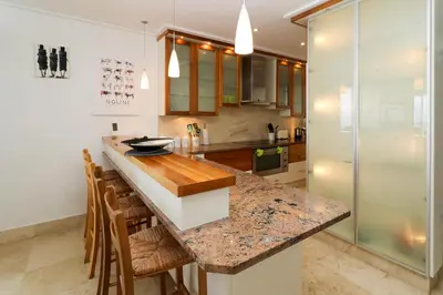 a kitchen with a marble counter top and wooden chairs at Hermanus Seaview Apartment in Hermanus