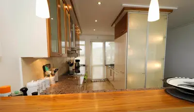 a kitchen with white cabinets and a wooden floor at Hermanus Seaview Apartment in Hermanus