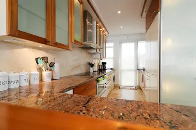 a kitchen with a marble counter top and wooden cabinets at Hermanus Seaview Apartment in Hermanus