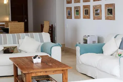 a living room with two white couches and a wooden table at Hermanus Seaview Apartment in Hermanus