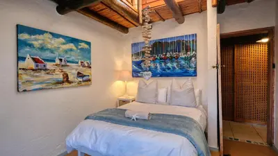 a bedroom with a bed with a painting on the wall at Rox Villa in Rooiels