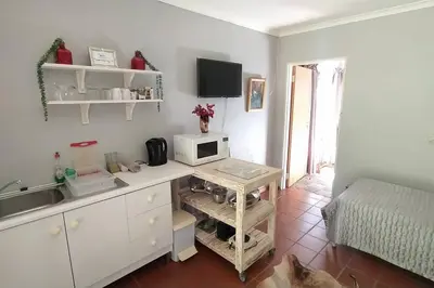 a kitchen with a desk with a microwave and a bed at Garden cottage in Cape Town