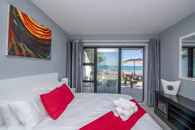a bedroom with a bed with red and white pillows at Cap du Mont in Bloubergstrand