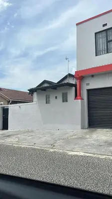 a white building with a garage door on the side of it at Naledi homestay in Cape Town