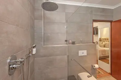 a bathroom with a shower and a toilet in it at Villa Venusta Luxury Guesthouse - Solar Power in Hermanus