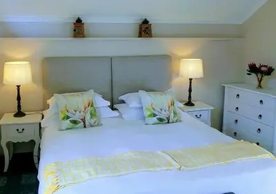 a bedroom with a white bed with two lamps at Aan De Vliet Guest House in Stellenbosch