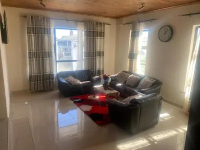 a living room with two couches and a clock on the wall at SABATH LODGE TWO in Cape Town