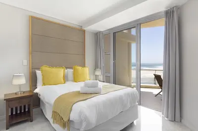 a bedroom with a large bed with a view of the ocean at Lagoon Beach 302A in Cape Town