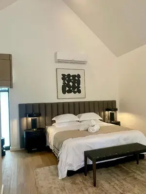 a bedroom with a large bed with white pillows at Mountain Cottages at Haskell Vineyard in Stellenbosch