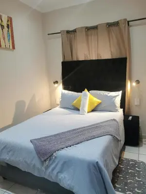 a bedroom with a large bed with blue sheets and yellow pillows at Sunrise Lodge in Cape Town
