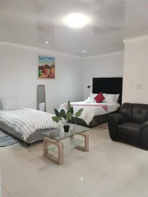 a living room with two beds and a couch at Sunrise Lodge in Cape Town