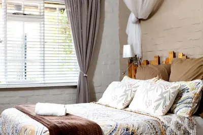 a bed in a bedroom with a window and a bedskirtspectspects at House of Perez in Wellington