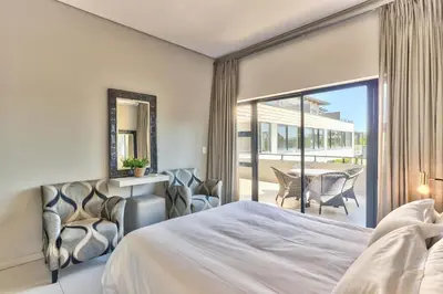 a bedroom with a bed and a view of a patio at Heritage Square Apartments in Durbanville