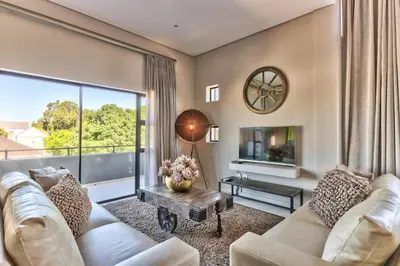 a living room with a couch and a large window at Heritage Square Apartments in Durbanville