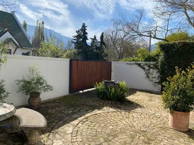 a backyard with a fence and a table and chairs at Courtyard on Weder in Greyton